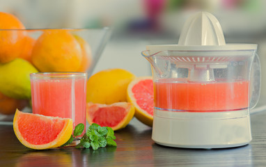 Glass of freshly squeezed grapefruit juice with juicer background.