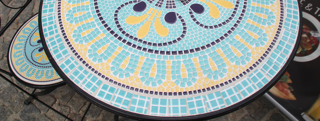 A table and a chair with blue and yellow mosaic tiles in the cafe. Bucharest,Romania - obrazy, fototapety, plakaty