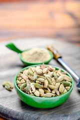Bowl with cardamom pots and cardamom powder, used for cooking and traditional medicine close up, spices collection