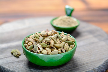 Bowl with cardamom pots and cardamom powder, used for cooking and traditional medicine close up, spices collection