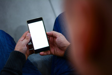 Online payment, digital banking. Men's hands are holding a white screen smartphone. A man holds a white screen phone while sitting in the waiting room.