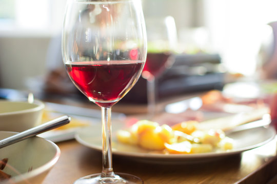Glass of red wine with french cheese and delicatessen in dinning room with wooden table and romantic light and cosy atmosphere. Thanksgiving Day. Christmas. Celebration. Selective focus. - Image