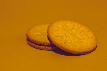 Obraz na płótnie Canvas Two round digestive biscuits on a brown background stacked one on top of the other