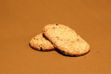 Two long round cornered digestive crackers one on top of the other on a brown paper with crumb on it