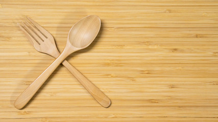 Wooden spoon and fork on wood table background. Top view. Eating food in the restaurant concept
