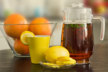 Pitcher and cup of hot black tea with mint, honey and lemons  the  background.