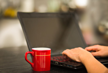 Woman working on laptop with cup of coffee.