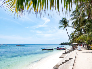 Amazing tropical beach background from Alona Beach at Panglao Bohol island with Beach chairs on the white sand beach with cloudy blue sky and palm trees. Philippines, november, 2018