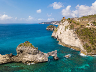 Fototapeta premium Aerial view to beautiful arched rock in ocean on Atuh beach. Photo from drone. Nusa Penida, Bali, Indonesia