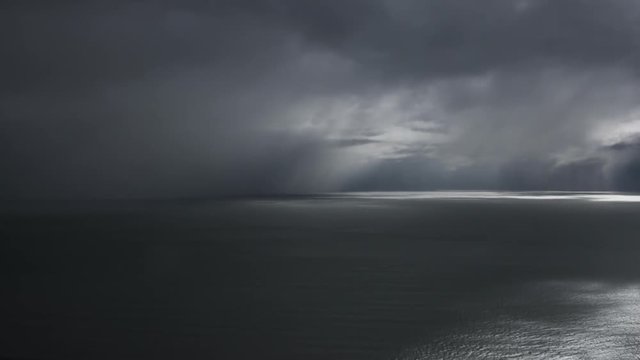Timelapse video of heavy rain and stormy clouds over the ocean, slowly covering the whole view with dark clouds.