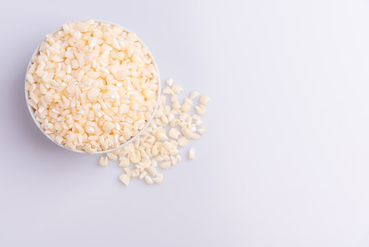 Dry uncooked white corn ingredient for Brazilian dessert sweet canjica / mungunza, white background, isolated, soft light. Festa Junina Party Brazilian Culture Concept Image.