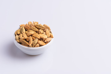 Dry Cardamom pod in a stone mortar, isolated on white background, latin term Elettaria cardamomum,  with copy space, angle view, soft light. 