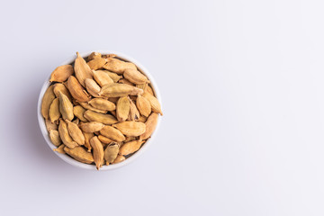 Dry Cardamom pod in a stone mortar, isolated on white background, latin term Elettaria cardamomum,  with copy space, angle view, soft light. 