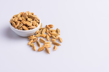 Dry Cardamom pod in a stone mortar, isolated on white background, latin term Elettaria cardamomum,  with copy space, angle view, soft light. 