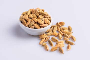 Dry Cardamom pod in a stone mortar, isolated on white background, latin term Elettaria cardamomum,  with copy space, angle view, soft light. 