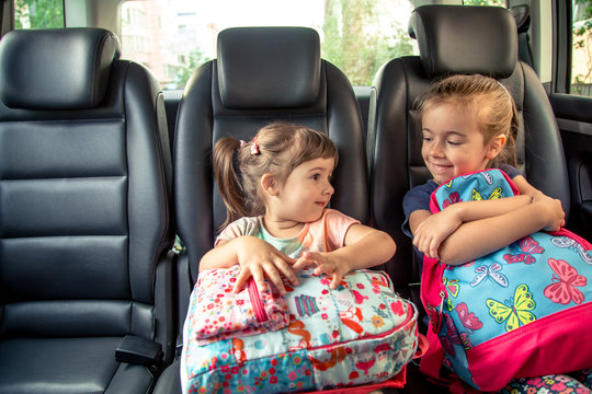 Children in the car go to school, happy, sweet faces of sisters