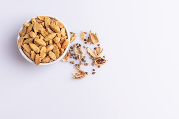 Dry Cardamom pod in a stone mortar, isolated on white background, latin term Elettaria cardamomum,  with copy space, angle view, soft light. 
