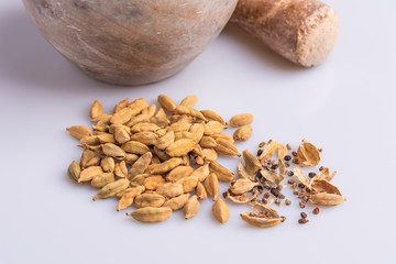 Dry Cardamom pod in a stone mortar, isolated on white background, latin term Elettaria cardamomum,  with copy space, angle view, soft light. 
