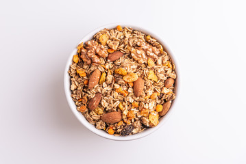 Granola or muesli with nuts and rasins in a white bowl on a white background, top view, soft light