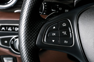 Fototapeta na wymiar Media and navigation control buttons on a steering wheel of a Modern car. Car interior details. Brown leather interior of the luxury modern car. Modern car interior. Car detailing