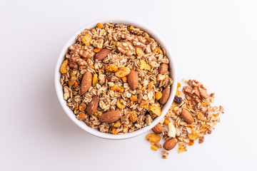 Granola or muesli with nuts and rasins in a white bowl on a white background, top view, soft light
