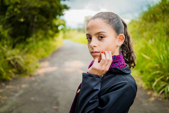 Pretty girl in black overcoat and purple scarf - old road in the background