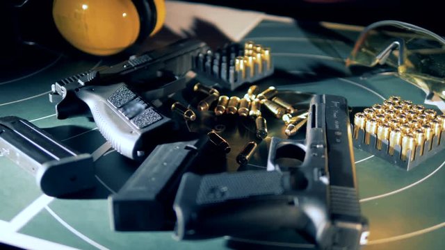 Guns, weapons with bullets on a table at a shooting gallery, close up.