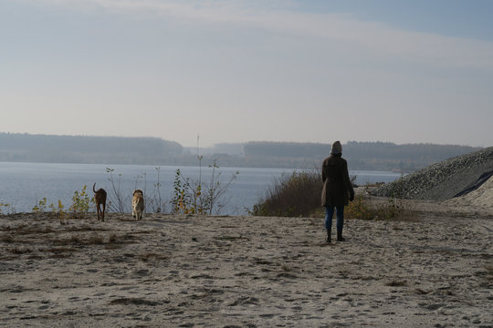 frau mann eingemummelt l&auml;uft gassi mit 2 hunden im winter kalten herbst 