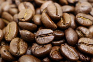 Closed up heap of roasted coffee beans with selective focus and blurred background  