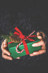 Woman's hands hold christmas or new year decorated gift box.