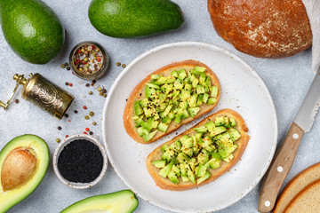 Slices of rye bread with avocado and spices colorful peppers and large sea salt, black sesame. Guacamole.  Sandwiches and ingredients on the table