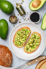 Slices of rye bread with avocado and spices colorful peppers and large sea salt, black sesame. Guacamole.  Sandwiches and ingredients on the table
