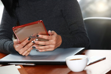 Businesswoman drinking coffee / tea and using tablet computer in a coffee shop
