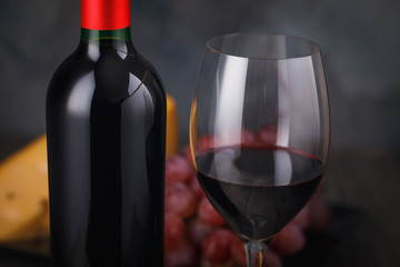 Bottle of red wine and filled glass on table close-up