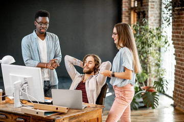 Fototapeta premium Group of young multi ethnicity coworkers dressed casually working together with computers and documents at the modern office interior