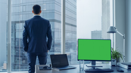 Confident Businessman in a Suit Contemplating Business Deal in His Office, Looking out of the...