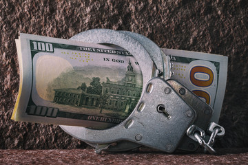 Dollars in handcuffs close-up. Concept on the limitation of currency circulation in different...
