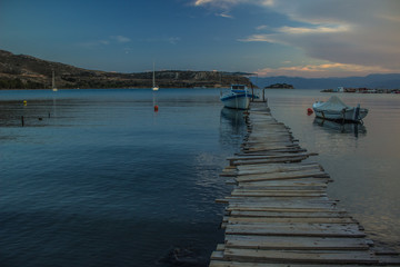Fototapeta premium evening twilight and atmospheric sea bay nature landscape place with poor wooden harbor of small pier for boats