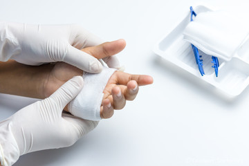 Woman doctor hands with gloves using cotton covering wound on the boy's palm