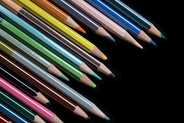 A pack of multicolored pencils on a dark background close up