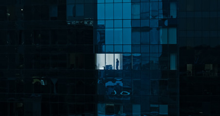 Aerial Shot: From Outside into Office Building with Businessman Working and Looking out of the...