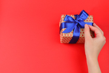 Present in woman hand on red background. 