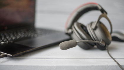 headphones with microphone on wooden grey background, laptop located in the background