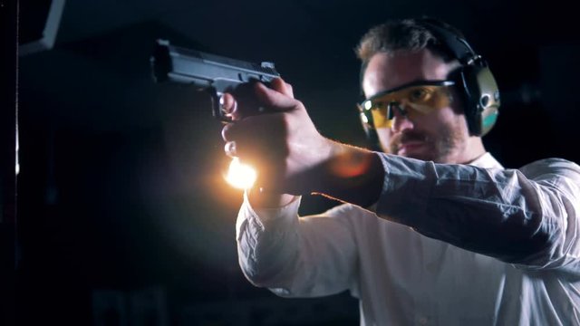 Man standing with a pistol in hands in a shooting room, shooting range.