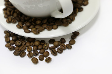 Coffee cup and roasted coffee beans on saucer, isolated on white background. Concept of breakfast, aroma, natural drink
