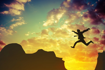 Obraz na płótnie Canvas Businessman jumps over rocky mountain. Business and success concept