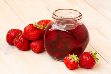 Strawberry jam in a jar with fresh strawberries on white wooden background. Glass jar with delicious strawberry confiture. Fresh homemade strawberry jam with berries in small jars, selective focus