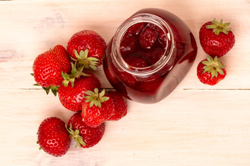 Strawberry jam in a jar with fresh strawberries on white wooden background. Glass jar and bowl with delicious strawberry confiture. Fresh homemade strawberry jam with berries in small jar. top veiw