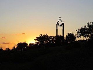 Beautiful Colorful Sunset Over Silhouette of Bell Tower with Cross and Four Bells