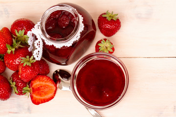 Strawberry jam in a jar with fresh strawberries on white wooden background. Glass jar and bowl with delicious strawberry confiture. Fresh homemade strawberry jam with berries in small jar. top veiw